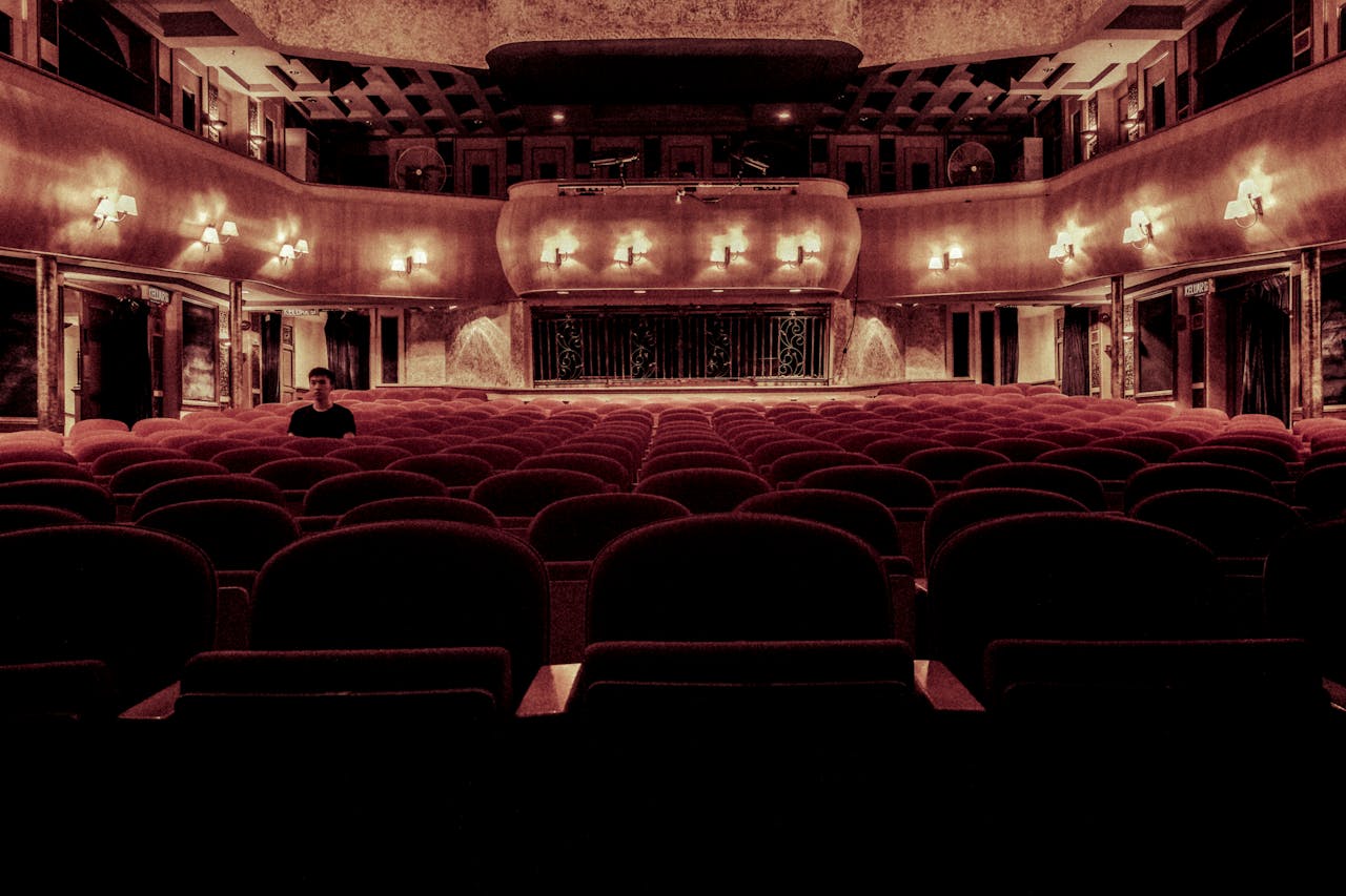 our-story-01 An elegant vintage theater with plush velvet seats and warm lighting, perfect for a serene cinematic experience.